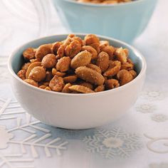 a white bowl filled with spiced peanuts on top of a blue and white table cloth