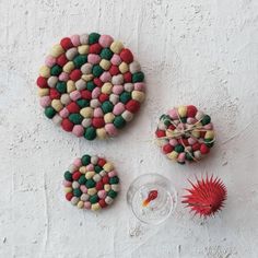 three pieces of art made out of felt sitting on top of a white wall next to other items