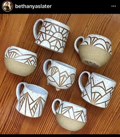 six white vases sitting on top of a wooden table