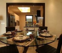 a glass table with plates and silverware on it in front of a kitchen area