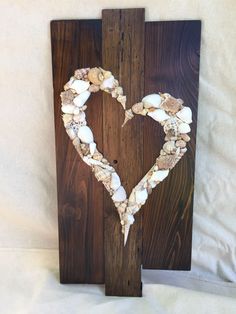 a heart made out of seashells sitting on top of a piece of wood