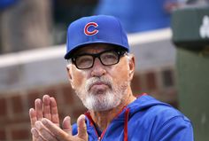 an older man wearing a chicago cubs hat and holding his hands up in the air