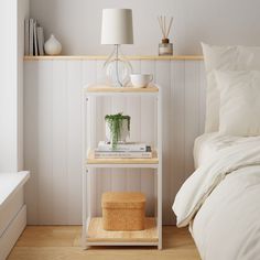 a white shelf next to a bed with pillows and a lamp on top of it