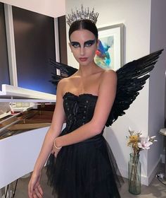 a woman in a black dress with wings on her head is posing for the camera