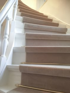 there is a cat that is sitting on the stair railing next to the carpeted stairs