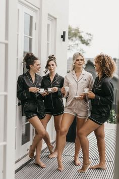 three women in black and white pajamas standing on a porch with their feet propped up