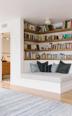 a living room filled with furniture and bookshelves next to a doorway that leads to a bedroom