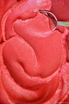 a close up of a cake with red frosting and a whisk in the middle