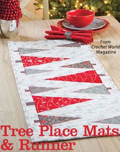 a table runner with red and white quilts on it next to a christmas tree