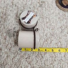 a roll of tape sitting on top of a floor next to a measuring tape