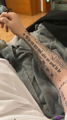 a person laying in bed with tattoos on their arm and leg, holding a cell phone