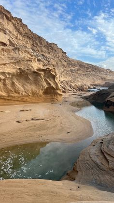 a river in the middle of a desert area with rocks and sand on both sides