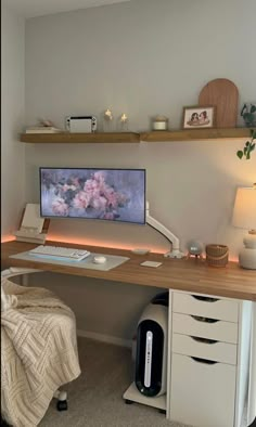 a desk with a computer on top of it and shelves above the desk, along with other items