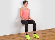 a woman sitting on top of a wooden floor next to a wall with her legs crossed