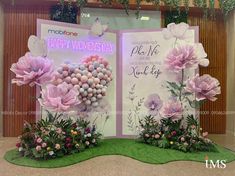 two large pink flowers on display in front of a happy women's day sign