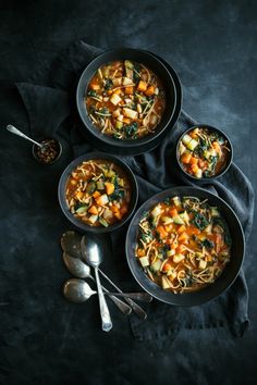 three bowls of soup on a table with spoons and silverware next to it