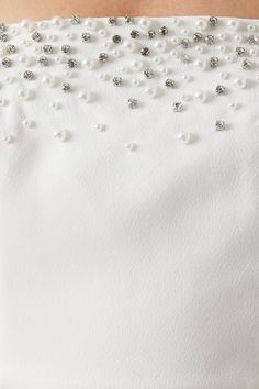 the back of a woman's white dress with pearls and beading on it