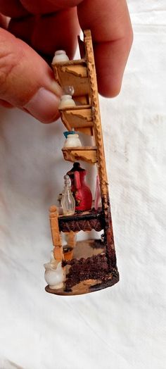 someone is holding a miniature ladder made out of wood