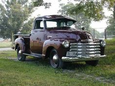 an old truck is parked in the grass