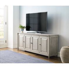 a flat screen tv sitting on top of a wooden entertainment center next to a blue rug