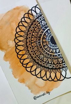 an orange and black art piece on top of a white paper with watercolor paint