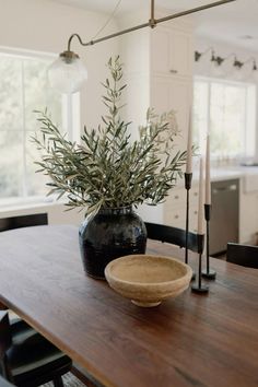 a wooden table topped with a black vase filled with greenery