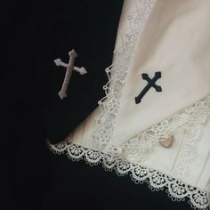 two white handkerchiefs with black crosses on them, one has a cross and the other has a crucifix