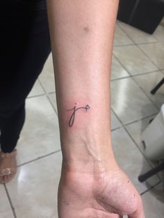 a woman's wrist tattoo with the letter j on her left hand and an arrow in the middle