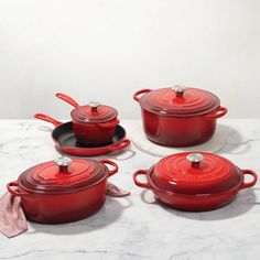 red pots and pans are sitting on a white table