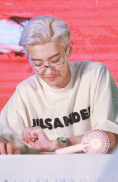 a man sitting at a table with a fan in front of him and looking down