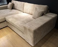 a beige corded sectional sofa sitting on top of a hard wood floor