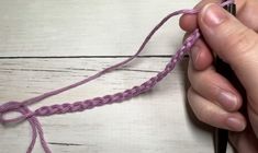 someone is working with yarn to make a crochet pattern on a piece of wood