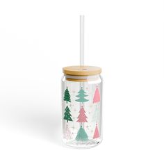 a glass jar with a wooden lid and a straw in the bottom filled with christmas trees