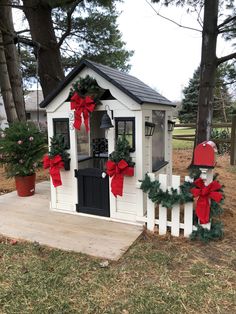 a small white house decorated with wreaths and bows