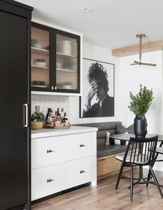 a kitchen with black and white cabinets, wood flooring and a dining room table