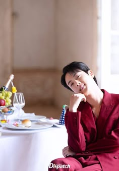 a woman sitting at a table with food and wine