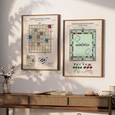 two framed maps hang on the wall next to a table with a vase and potted plant