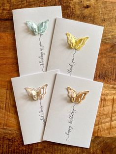 four different colored butterflies on white cards