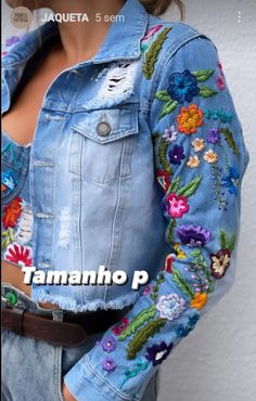 a woman wearing a jean jacket with flowers on it