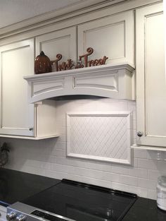 a stove top oven sitting inside of a kitchen next to white cabinets and counter tops