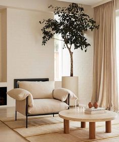 a living room with a tree in the corner next to a couch and coffee table