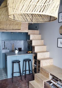 a kitchen area with stools, counter and stairs leading up to the upper floor