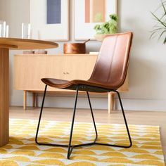 a brown chair sitting on top of a wooden floor next to a yellow and white rug