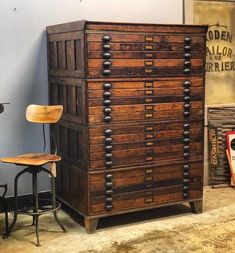 an old wooden filing cabinet sitting next to a chair