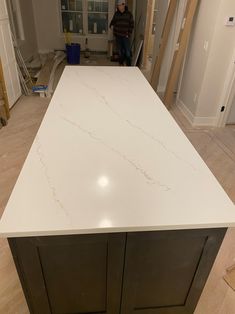 a kitchen counter top in the middle of a room under construction with a man standing behind it