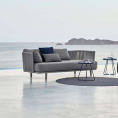 an outdoor seating area with two chairs and a table next to the ocean on a sunny day