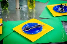 there are place settings on the table with forks and knives in blue plates, green napkins