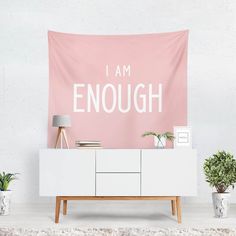 a pink and white wall tapestry with the words i am enough on it in front of a dresser