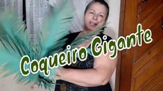 a woman in a black dress holding a green feathered object with the words coqueiro gigantee on it