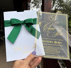 a person holding up a wedding card with a green bow on it's side